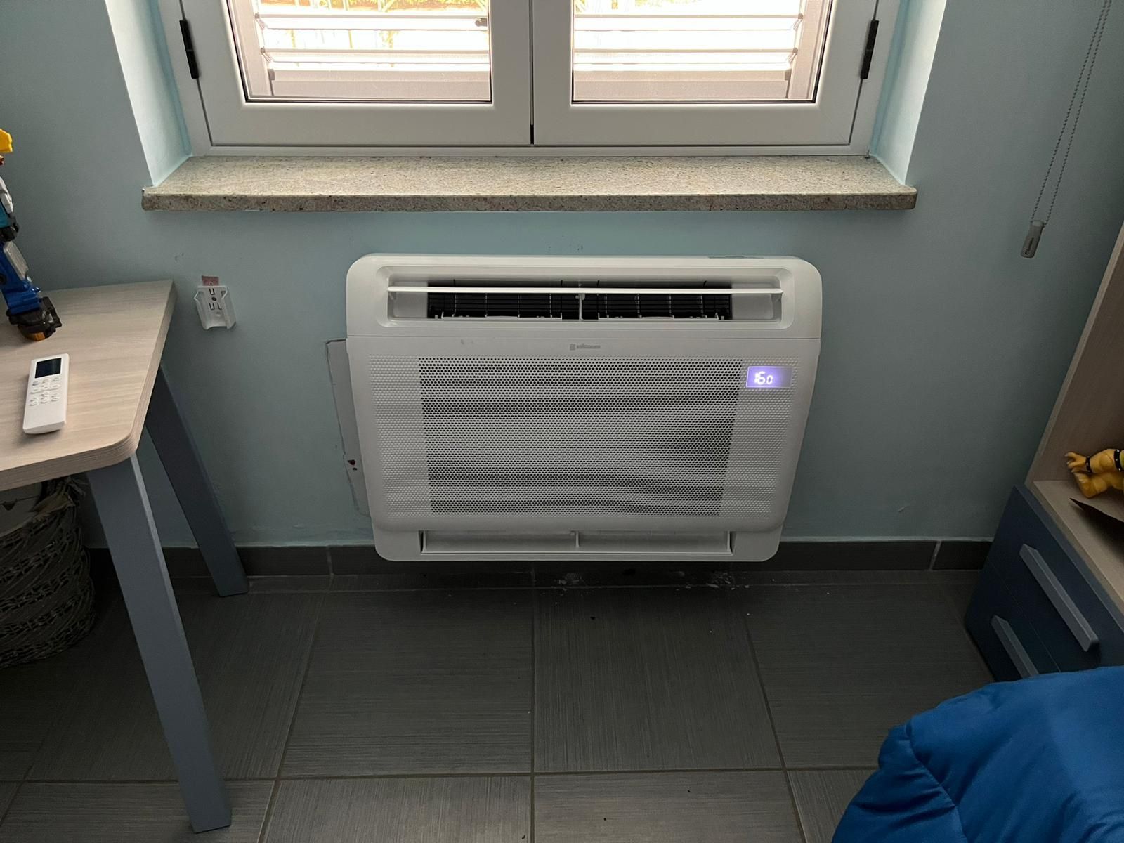 Una stanza con una finestra e un ventilatore sul muro.