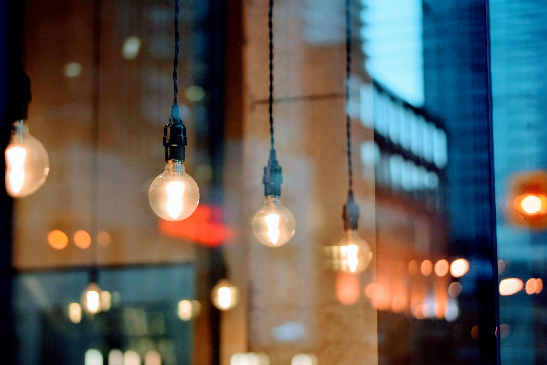 A bunch of light bulbs hanging from the ceiling in front of a window.