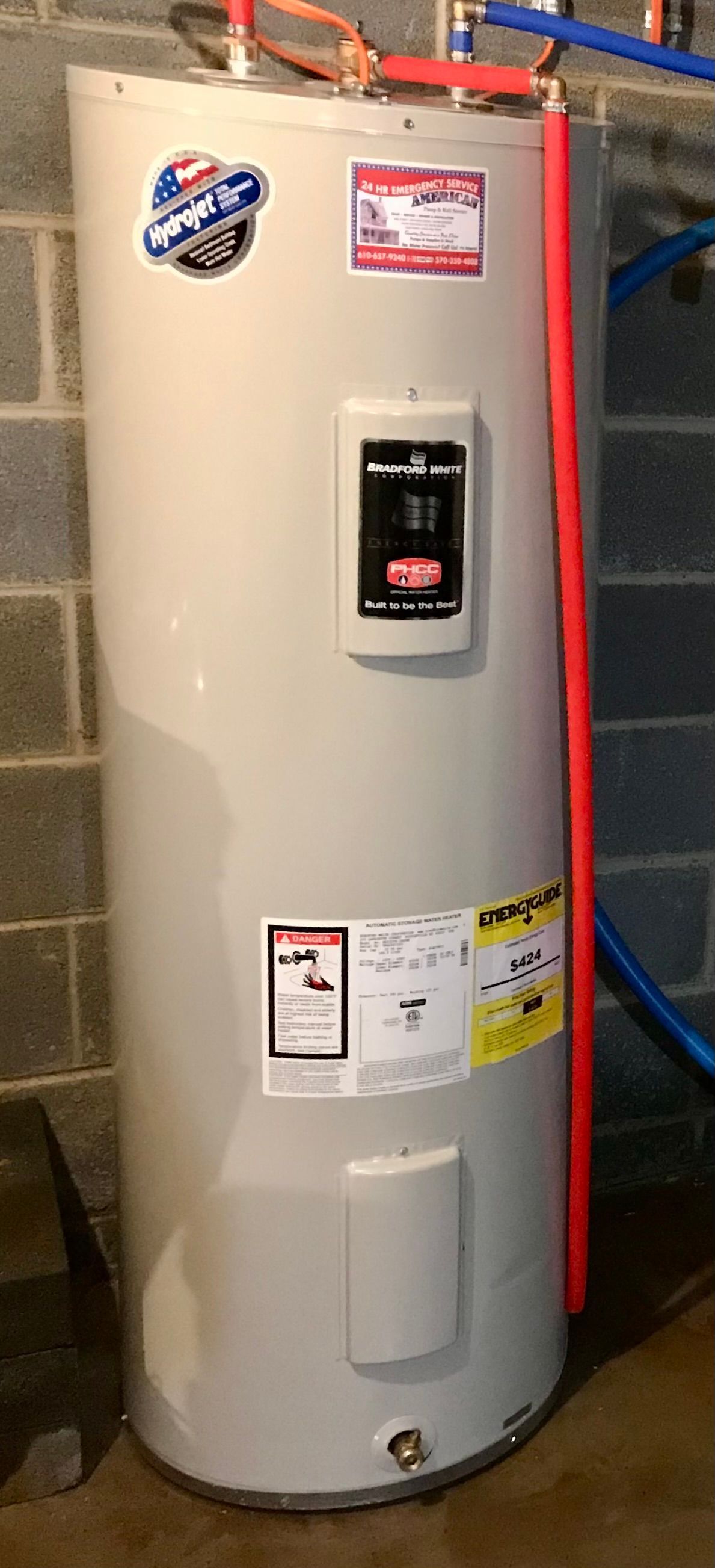 Tall beige water heater with labels and a digital control panel in a utility room