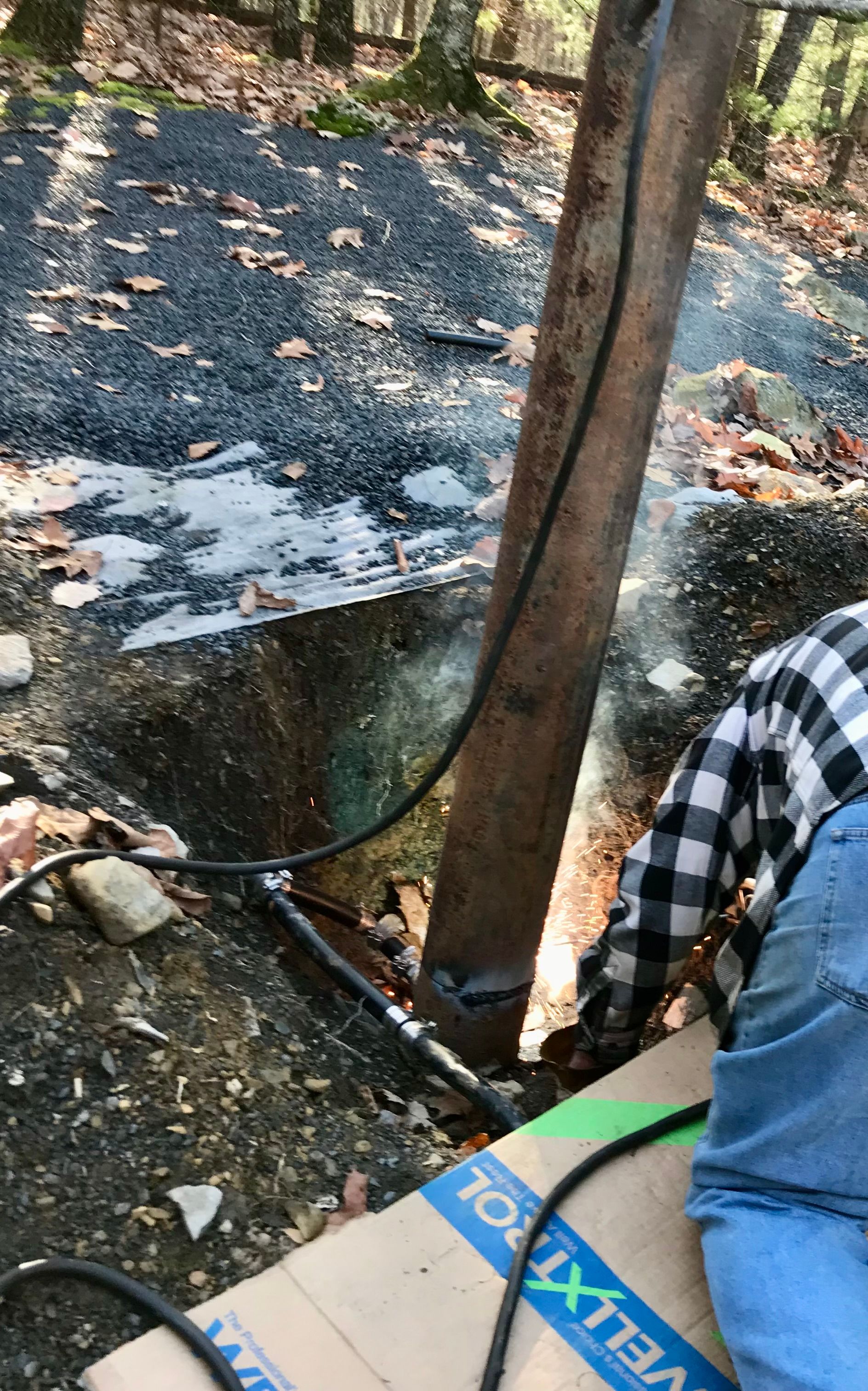 A charred outdoor area with a tree trunk, burnt ground, and debris near a blue box and checkered cloth.