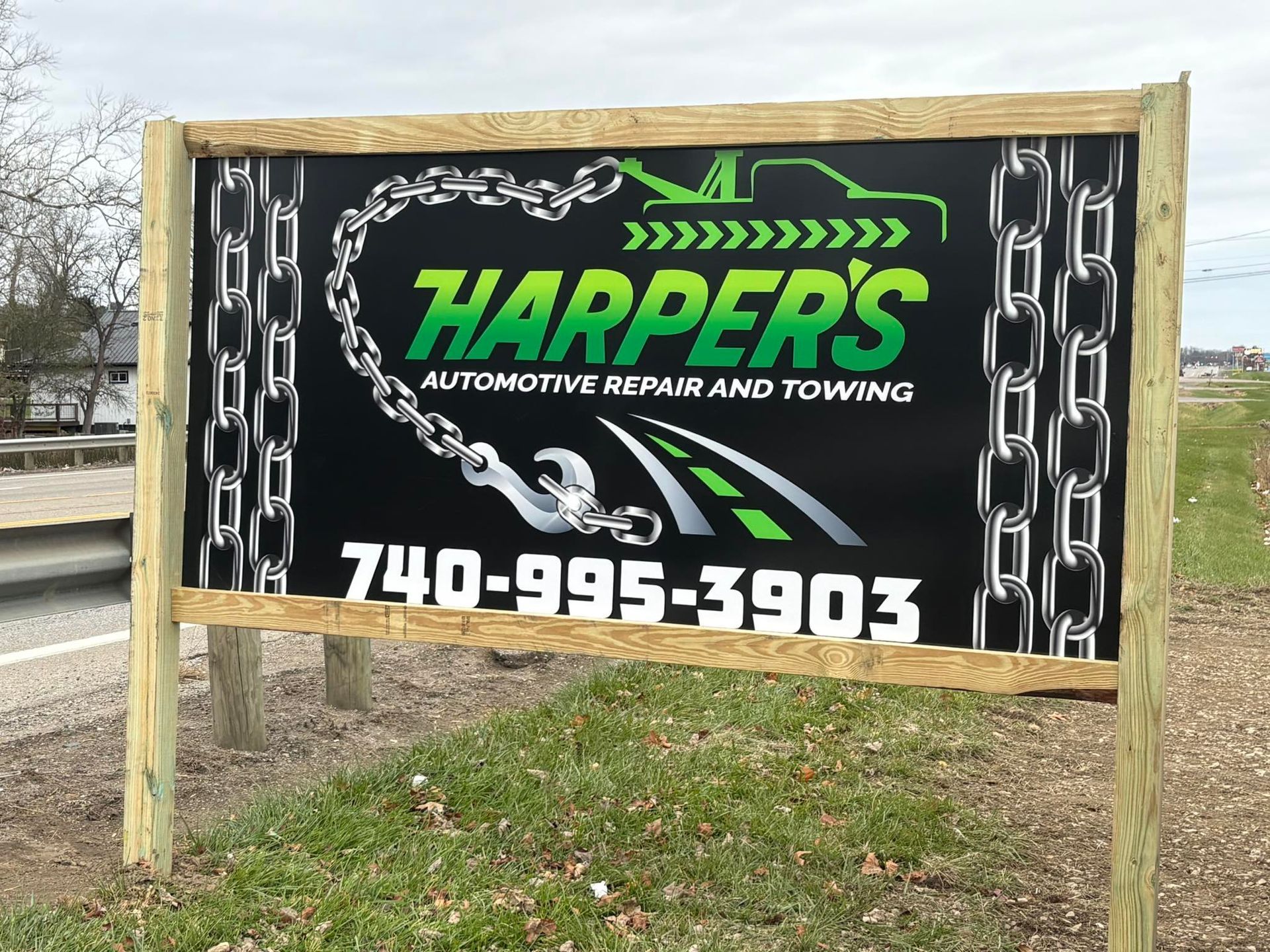 Harper's Automotive Towing sign with green logo, chain graphics, and phone number 740-995-3903