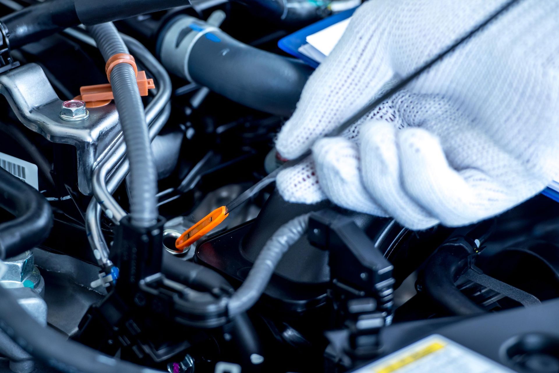 Gloved hands using tools to work on a car engine in a garage