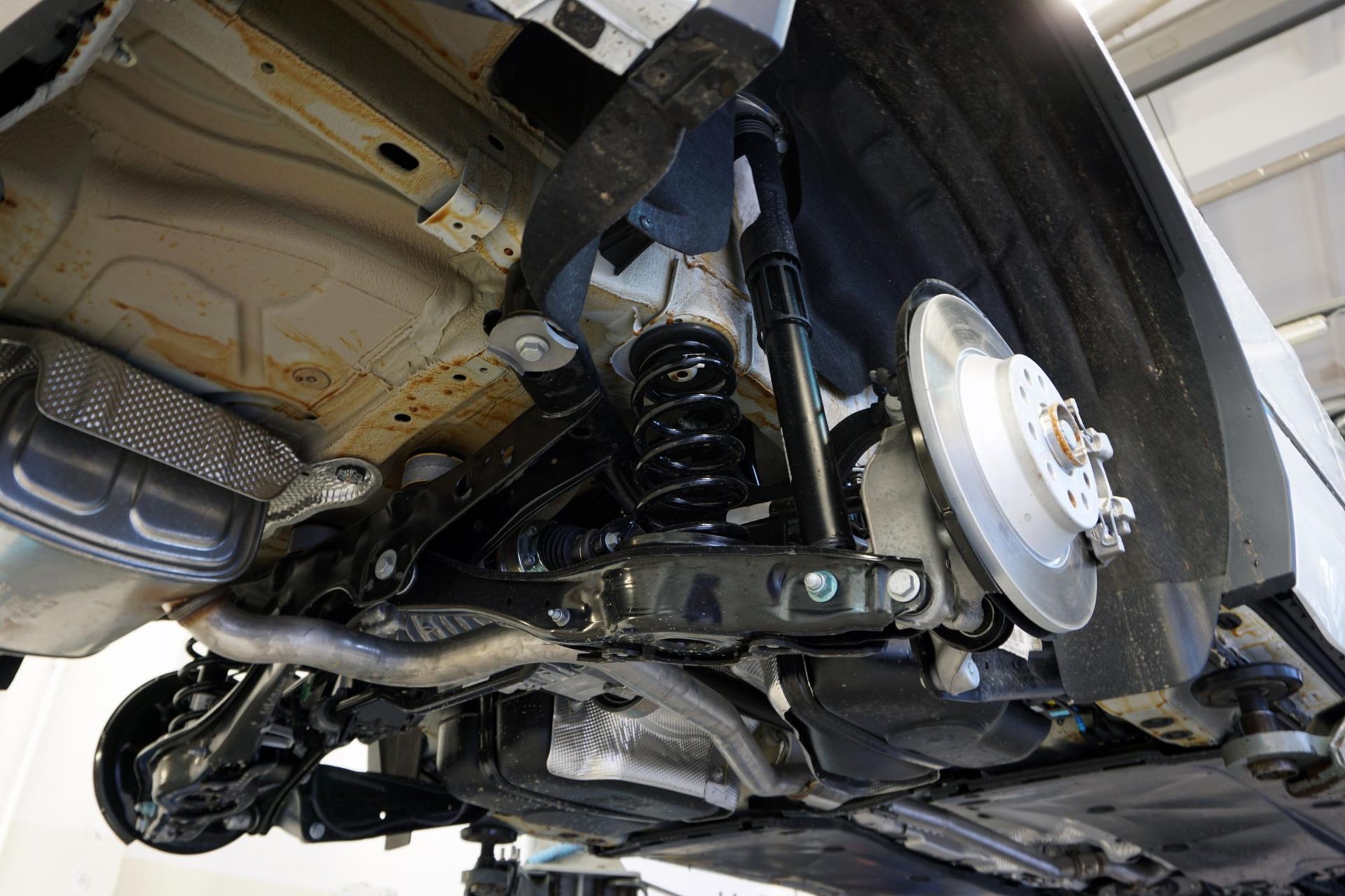 Undercarriage of a vehicle showing suspension, exhaust, and rear wheel assembly