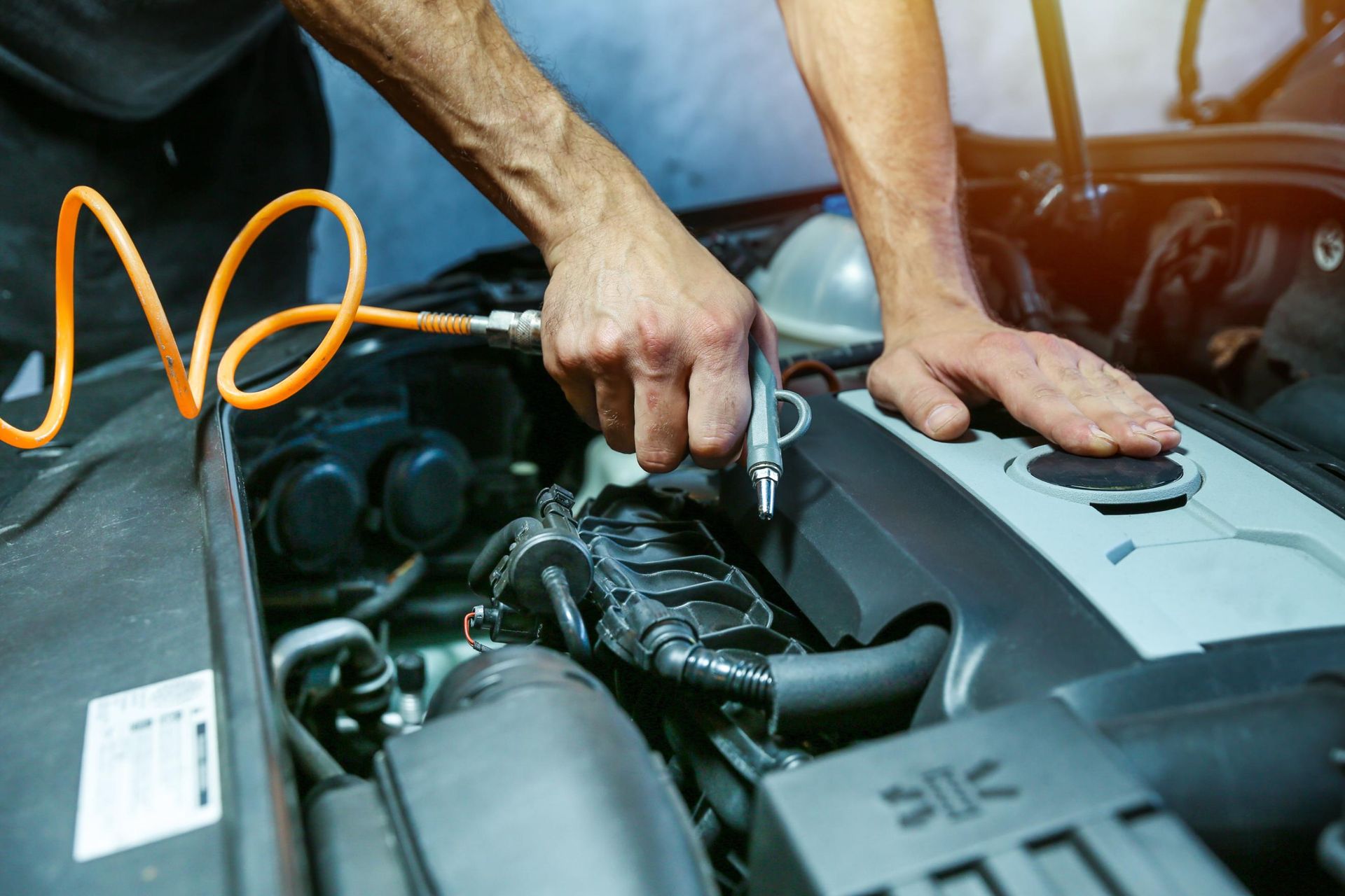 Mechanic using a ratchet wrench to work on a car engine under the hood
