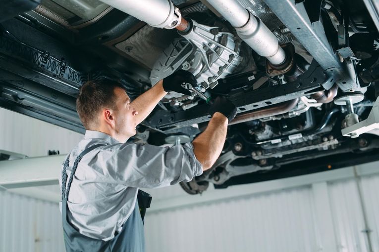 Mechanic inspecting a vehicle’s undercarriage on a lift in a garage
