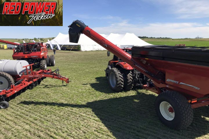 A red power tractor is parked in a grassy field