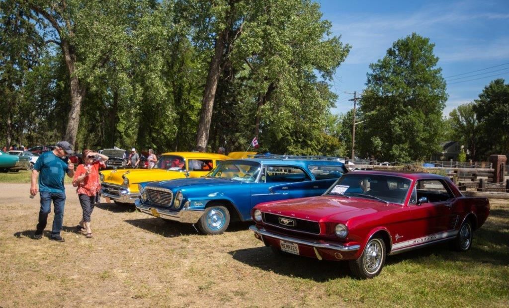 A red mustang is parked next to a blue car at a car show.