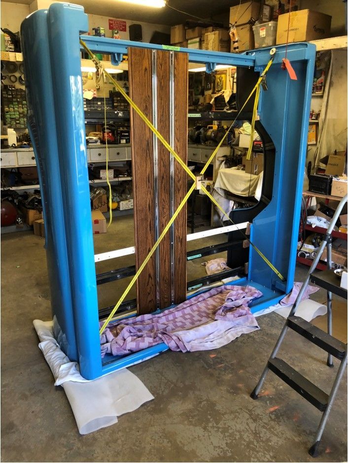 A large blue object is sitting in a garage next to a ladder