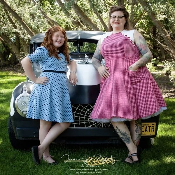 Two women standing next to a car with a license plate that says eatr