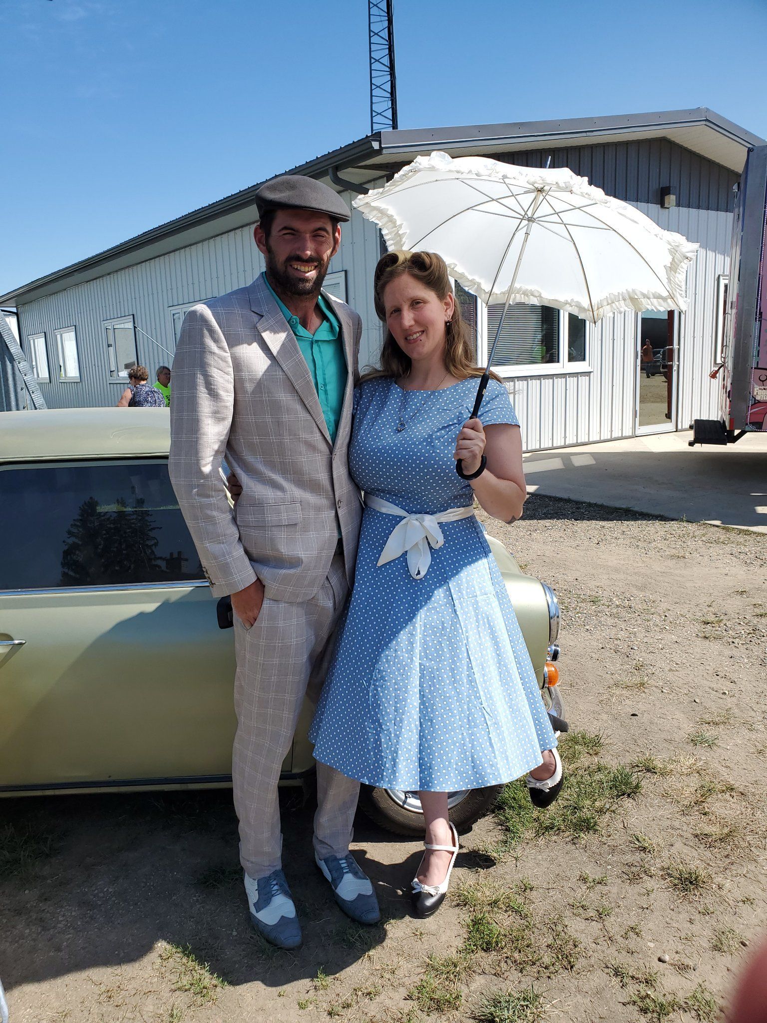 A man and a woman are standing next to a car holding an umbrella.