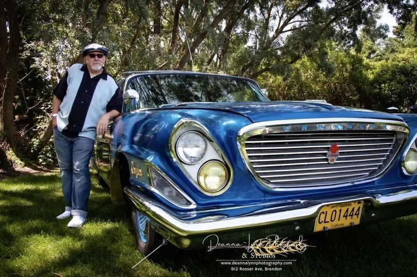 A man is standing next to a blue car with a license plate that says clo1441