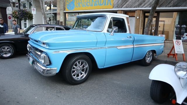 A blue truck is parked on the side of the road