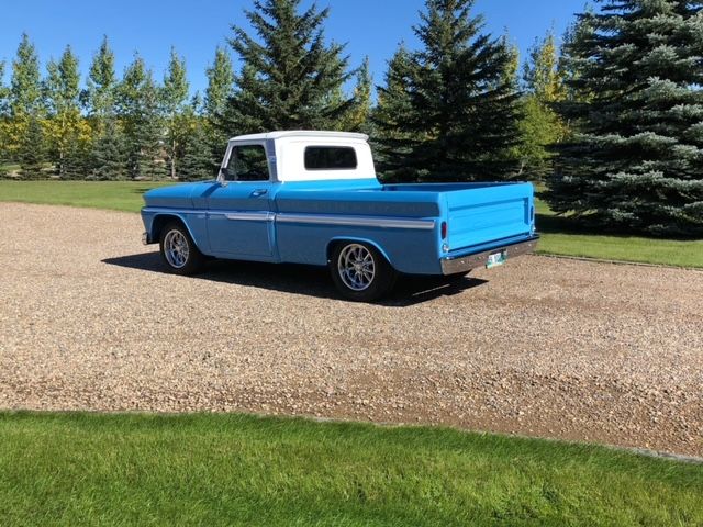 A blue and white truck is parked on a gravel road.