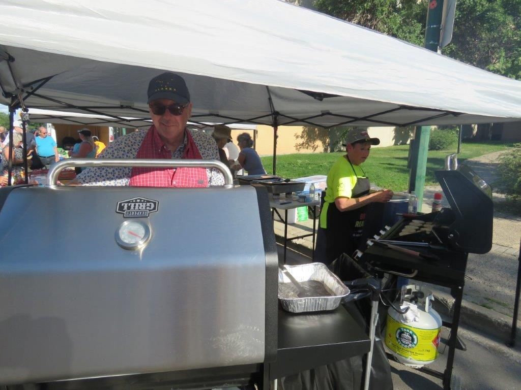 A man is cooking on a grill under a tent.