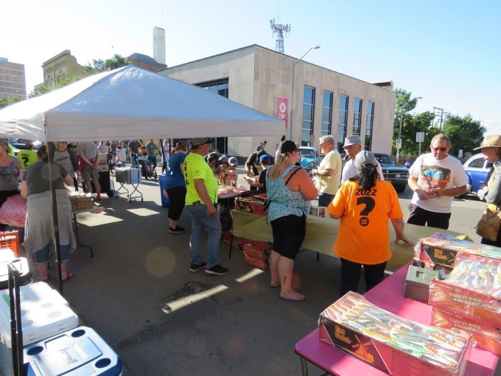 A group of people are standing around tables under a tent.