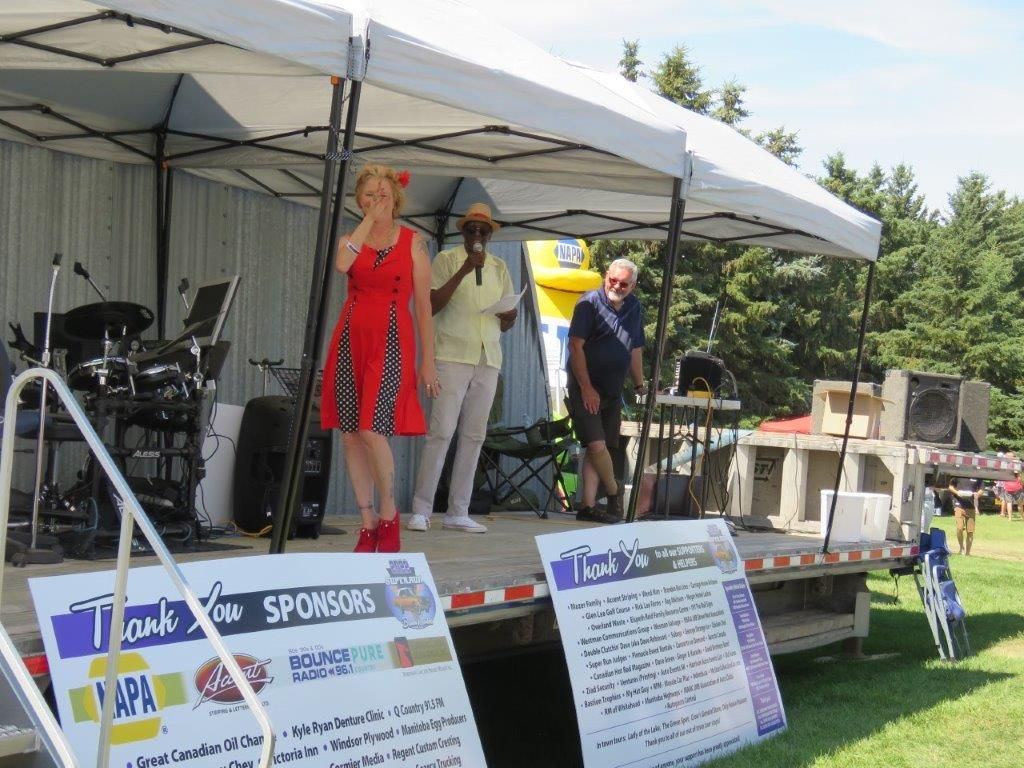 A woman in a red dress is standing on a stage in front of a sign that says sponsors.