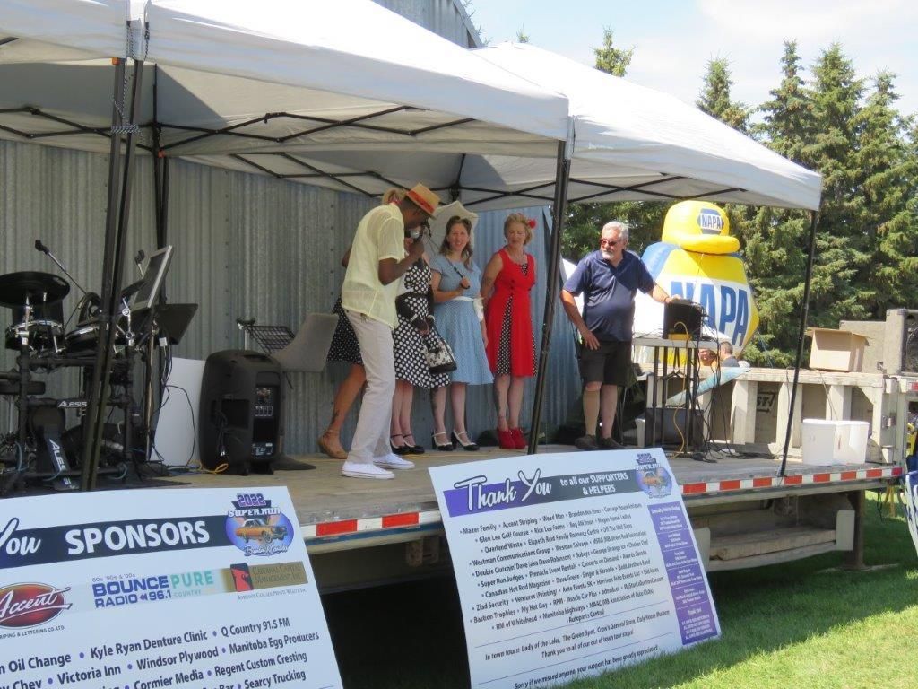 A group of people are standing on a stage in front of a sign that says sponsors.