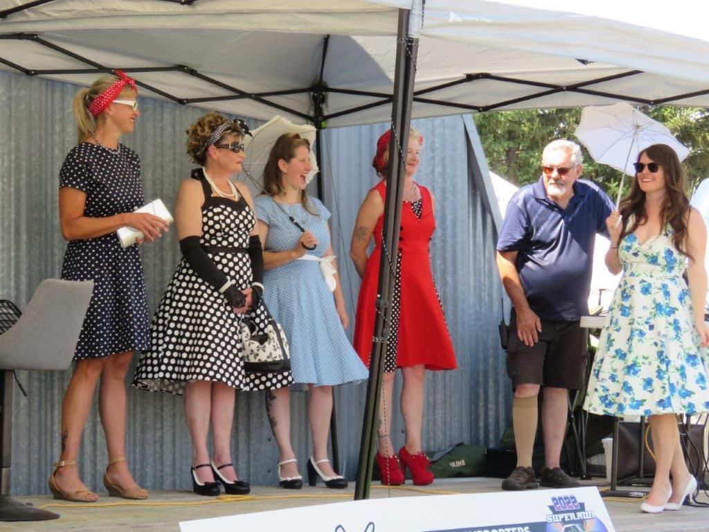 A group of women are standing on a stage under a tent.