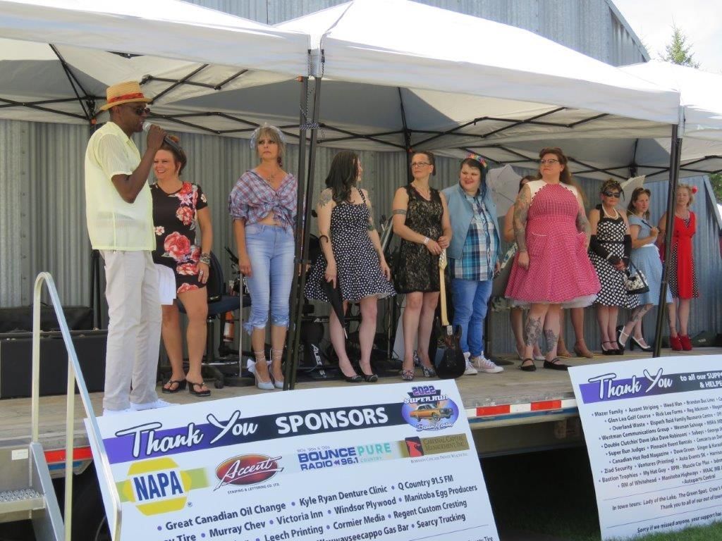 A group of people are standing on a stage in front of a thank you sign.