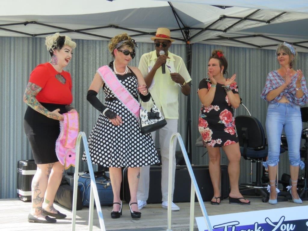 A group of women are standing on a stage in front of a sign that says thank you