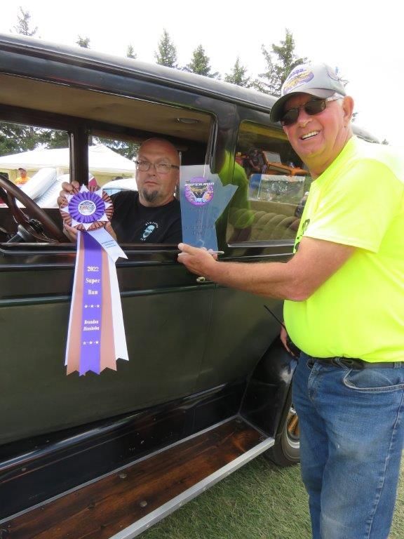 A man in a yellow shirt is giving a ribbon to another man in a car