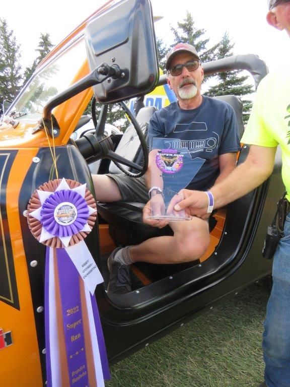 A man is sitting in a car holding a purple ribbon