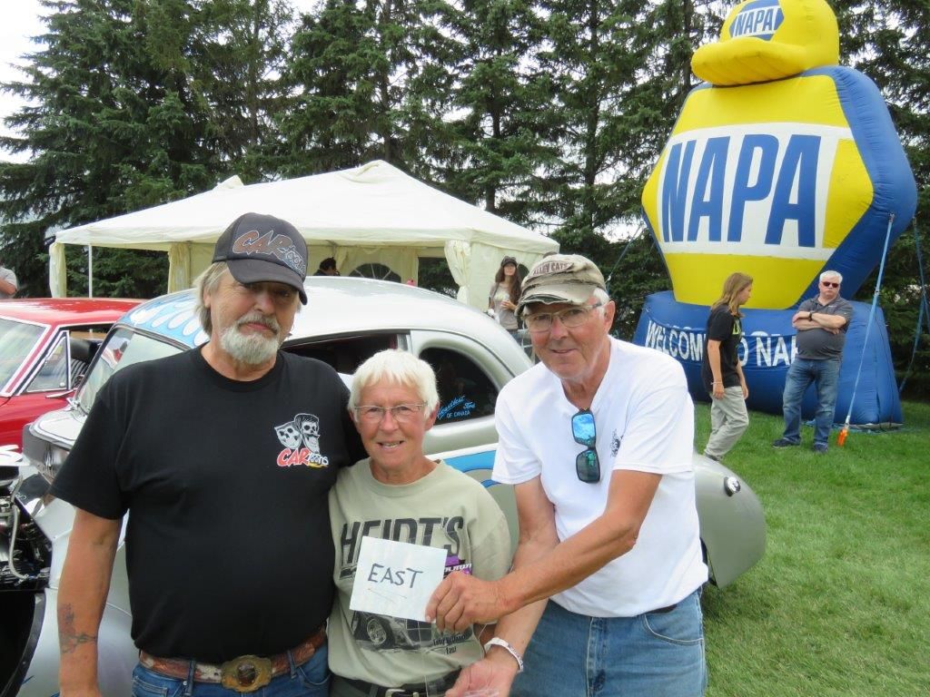 Three men are posing for a picture in front of a napa balloon