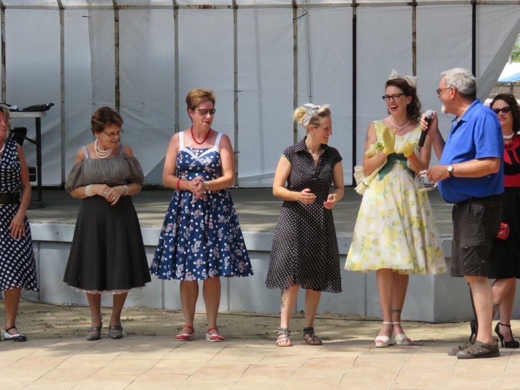 A group of women in dresses are standing next to each other on a stage.