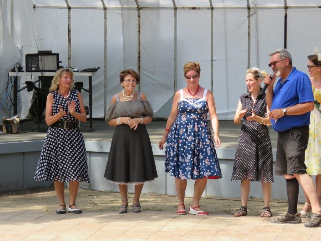 A group of women in polka dot dresses are standing next to each other on a stage.
