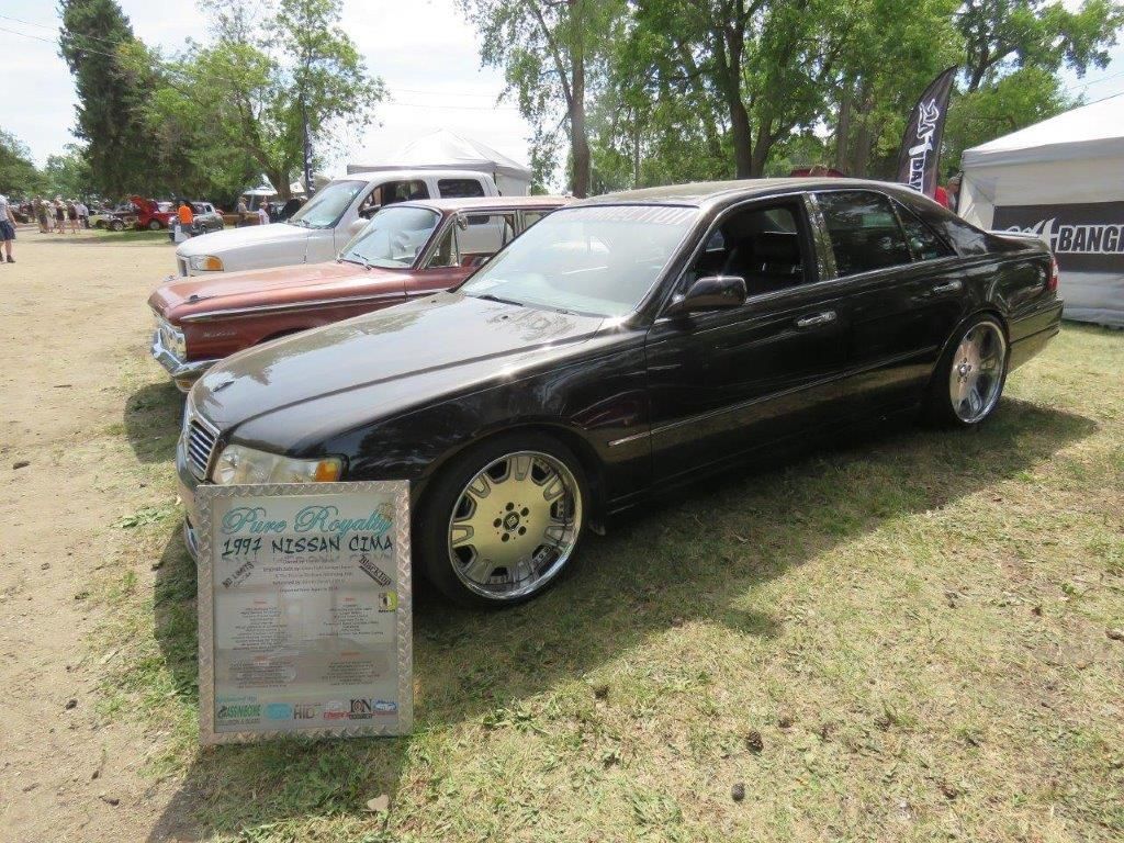 A black car is parked next to a red car at a car show.