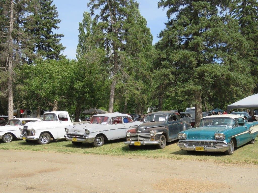A row of old cars are parked in a grassy area