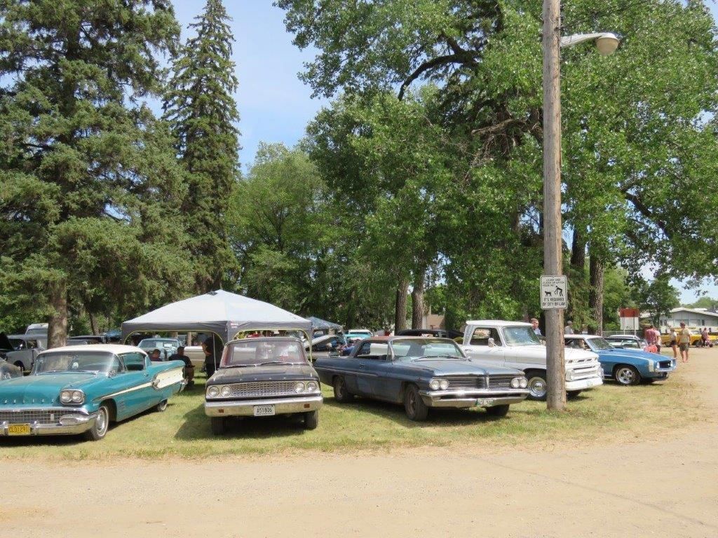 A row of old cars are parked in a grassy area.