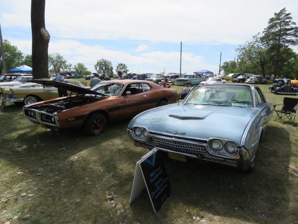 Two old cars are parked next to each other at a car show.