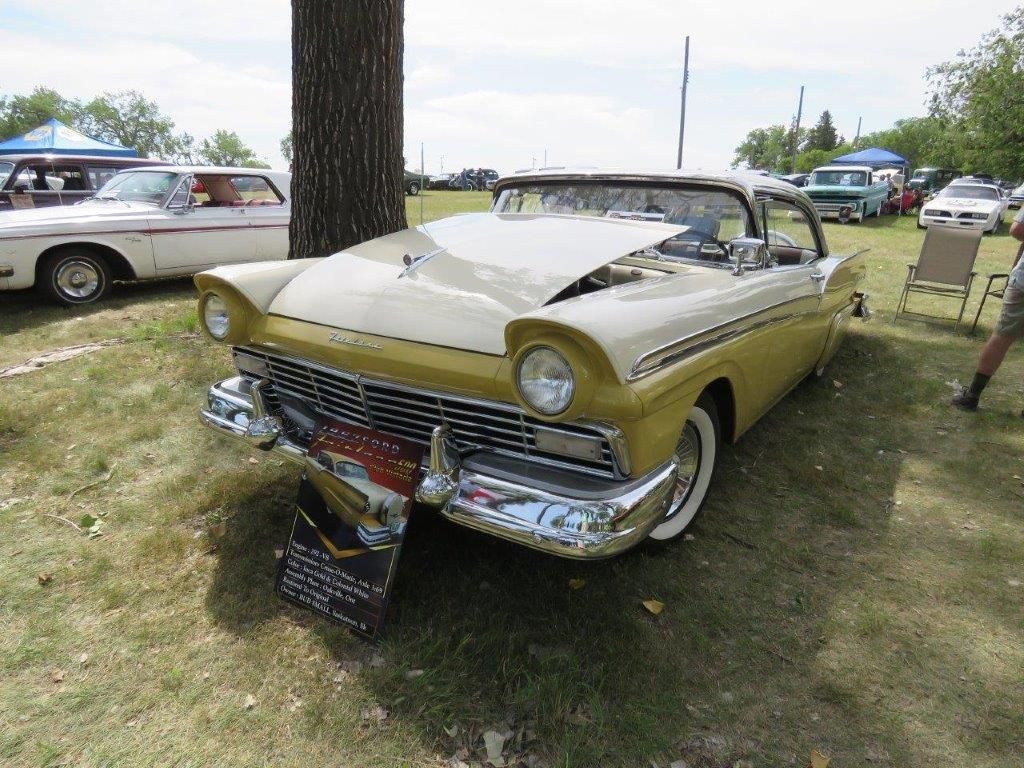 A yellow and white car is parked in a grassy field.