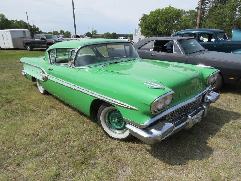 A green car is parked in a grassy field