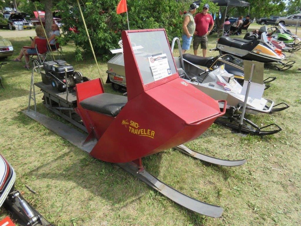 A red snowmobile is parked in a grassy field.