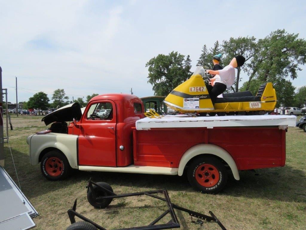 A man is riding a snowmobile in the back of a red truck.