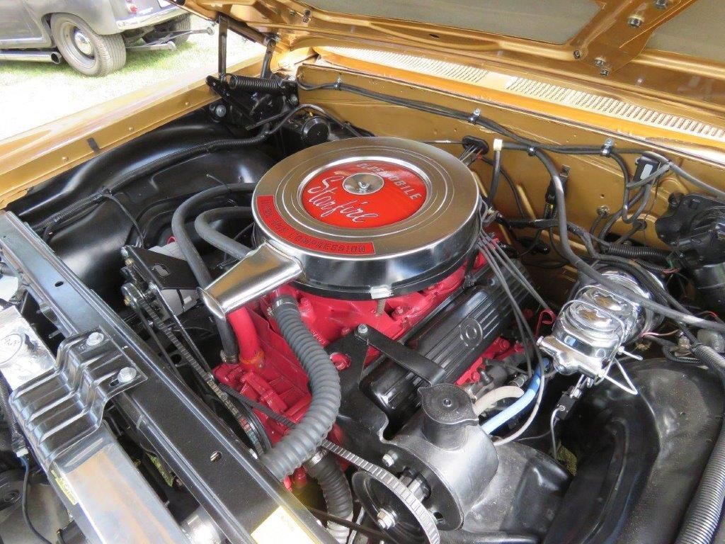 A close up of a car engine with a hood open.