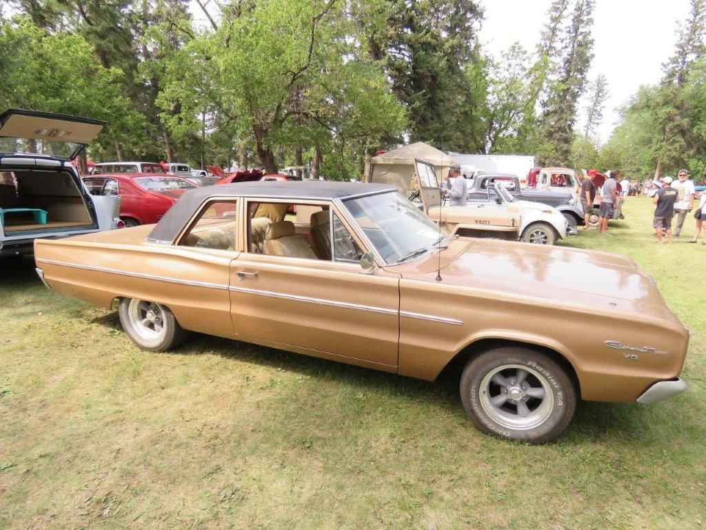 A brown car is parked in a grassy field at a car show.