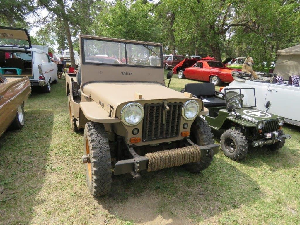 A jeep is parked next to a smaller jeep at a car show.