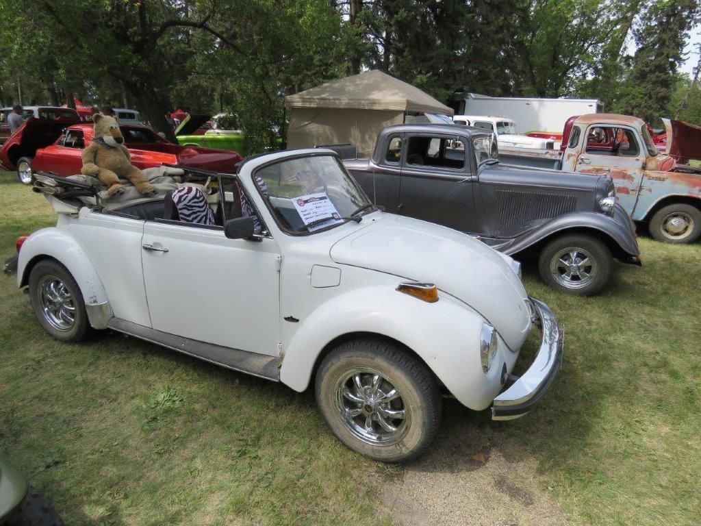 A white beetle convertible is parked next to a black car