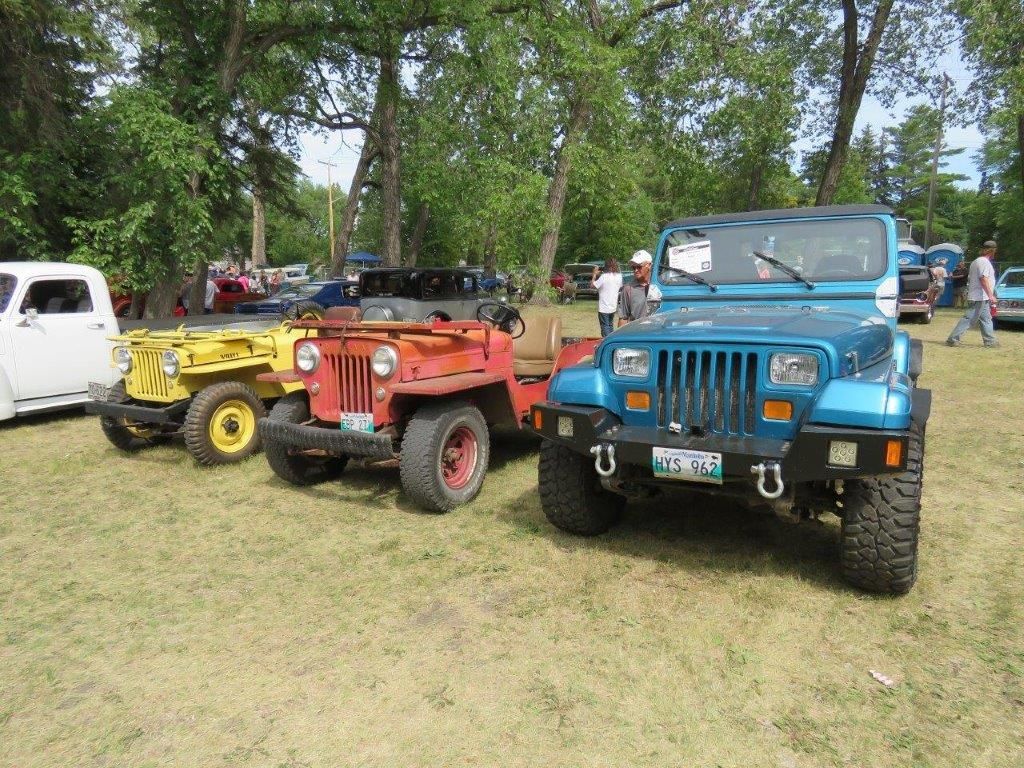 A group of jeeps are parked in a grassy field.