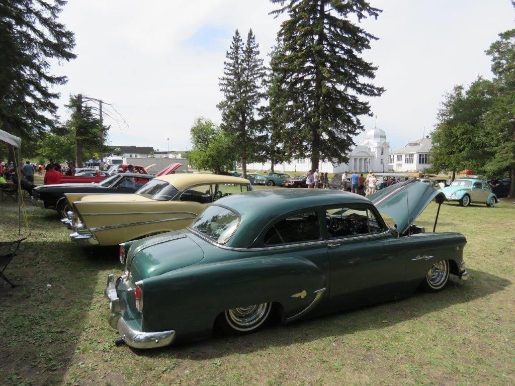 A row of old cars are parked in a grassy field.