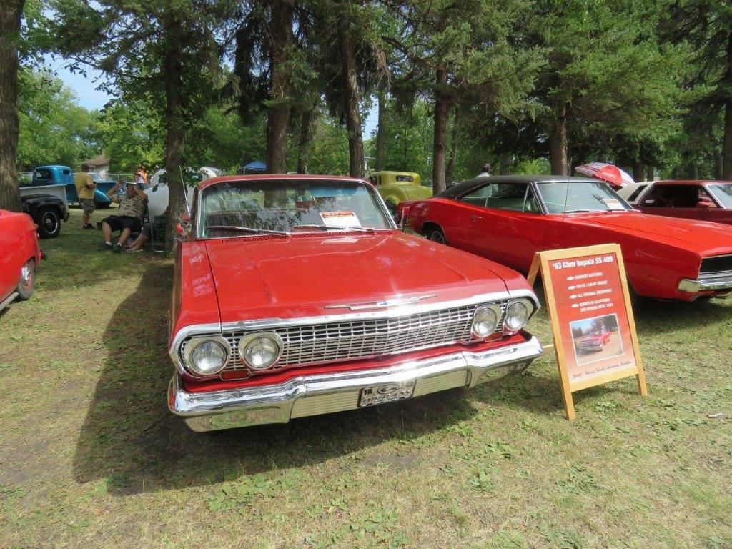 A red car is parked next to another red car at a car show.
