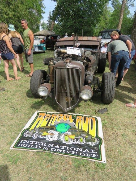 A group of people are looking at a hot rod on display at a car show.