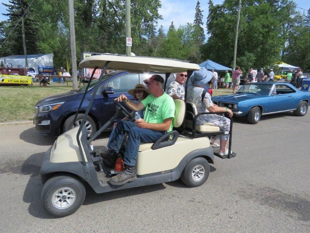 A man in a green shirt is driving a golf cart
