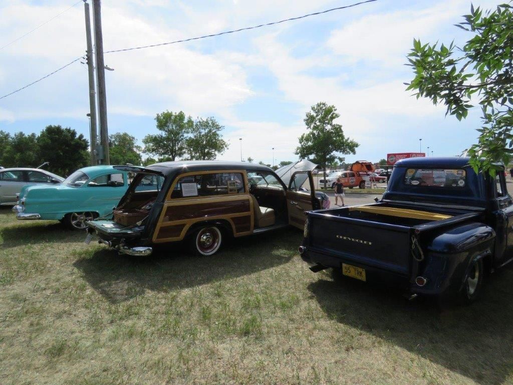 Two old cars and a truck are parked in a grassy field.