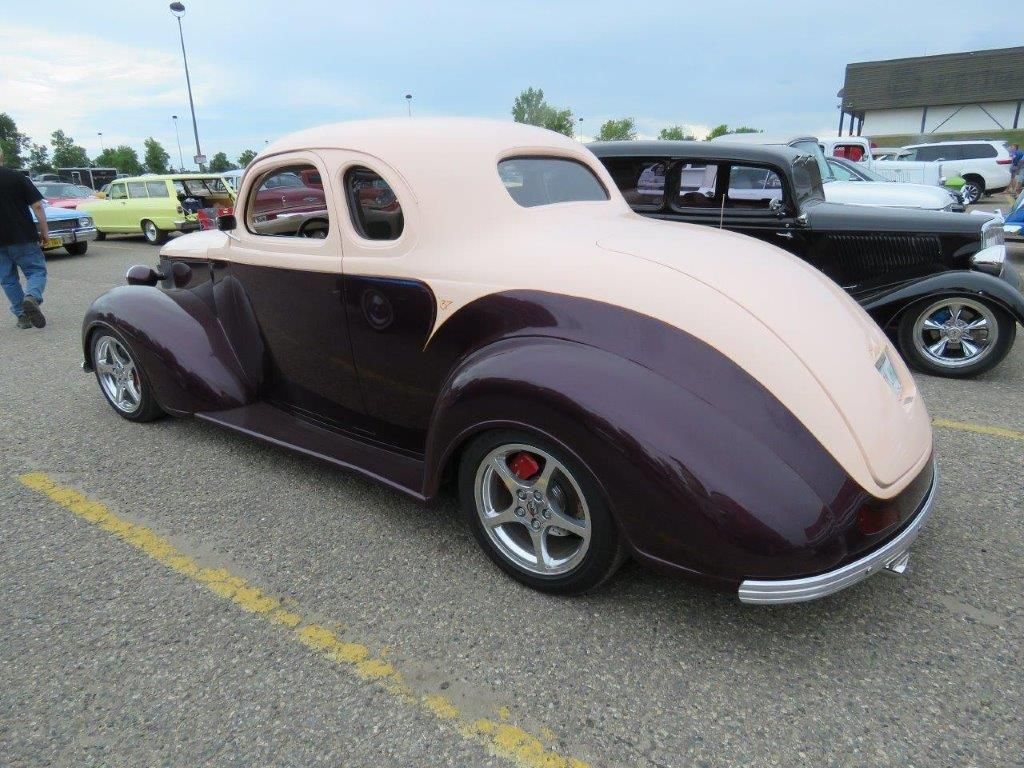 A pink and purple car is parked in a parking lot