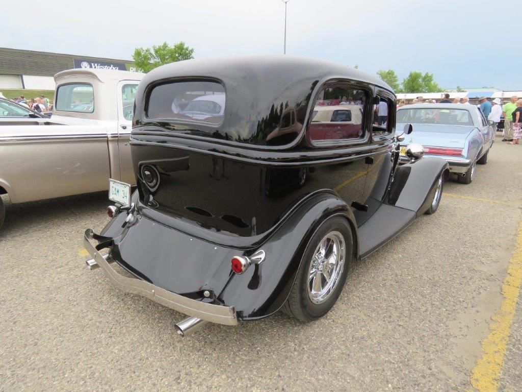A black car is parked in a parking lot next to another car.