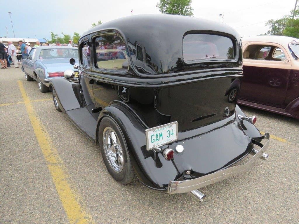 A black car with a license plate that says gm is parked in a parking lot.